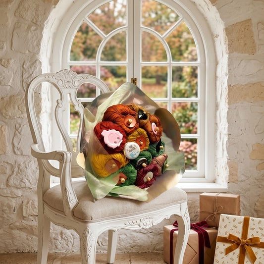 A large bouquet of knitting yarn, displayed on an ornate white armchair in front of a stone wall and arched window. Two wrapped gift boxes sit on the floor to the right.