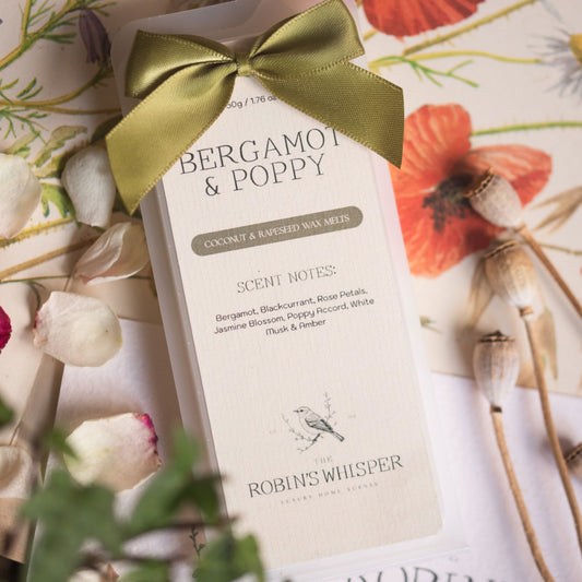 Bergamot & Poppy wax melt product packaging with a green ribbon on a floral background
