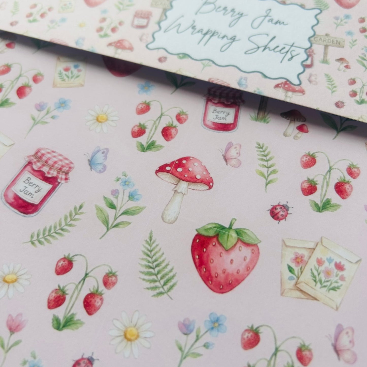 Berry Jam wrapping sheets with strawberry, mushroom, and jar designs on a pink background.