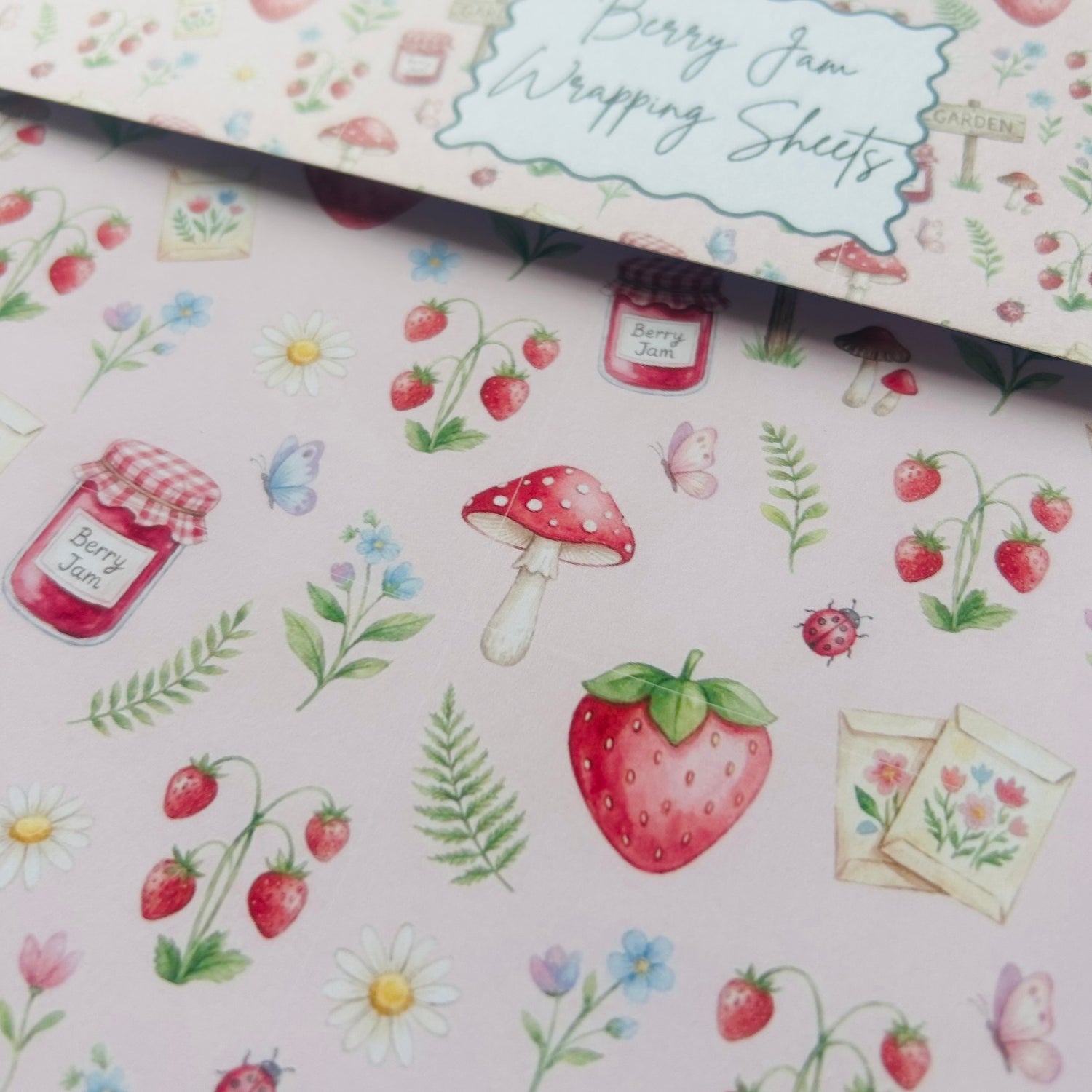 Berry Jam wrapping sheets with strawberry, mushroom, and jar designs on a pink background.