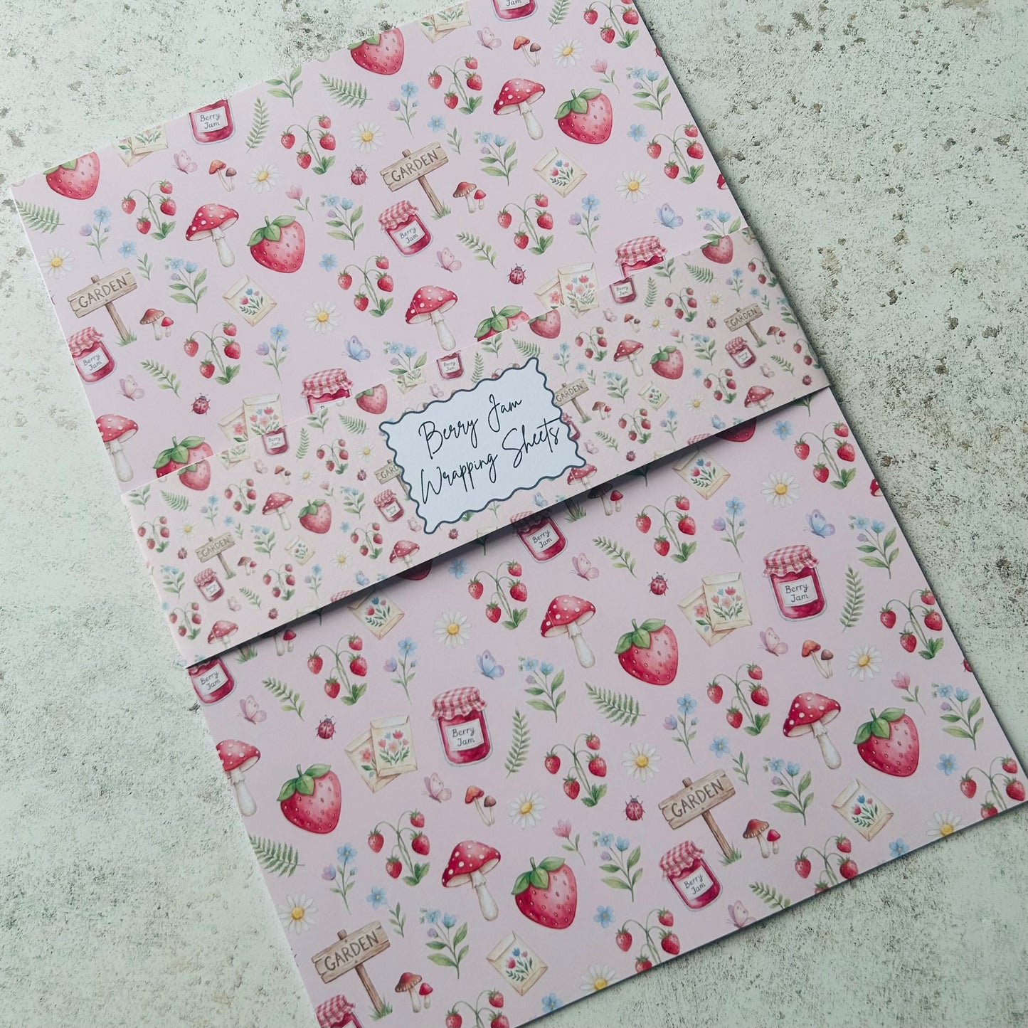 Two sheets of paper with a colourful strawberry pattern on a textured surface