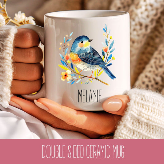 A double-sided ceramic mug with a bird design and the name 'Melanie' printed on it.