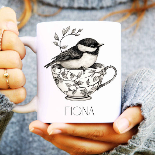 Person holding a mug with a bird design and 'Fiona' text
