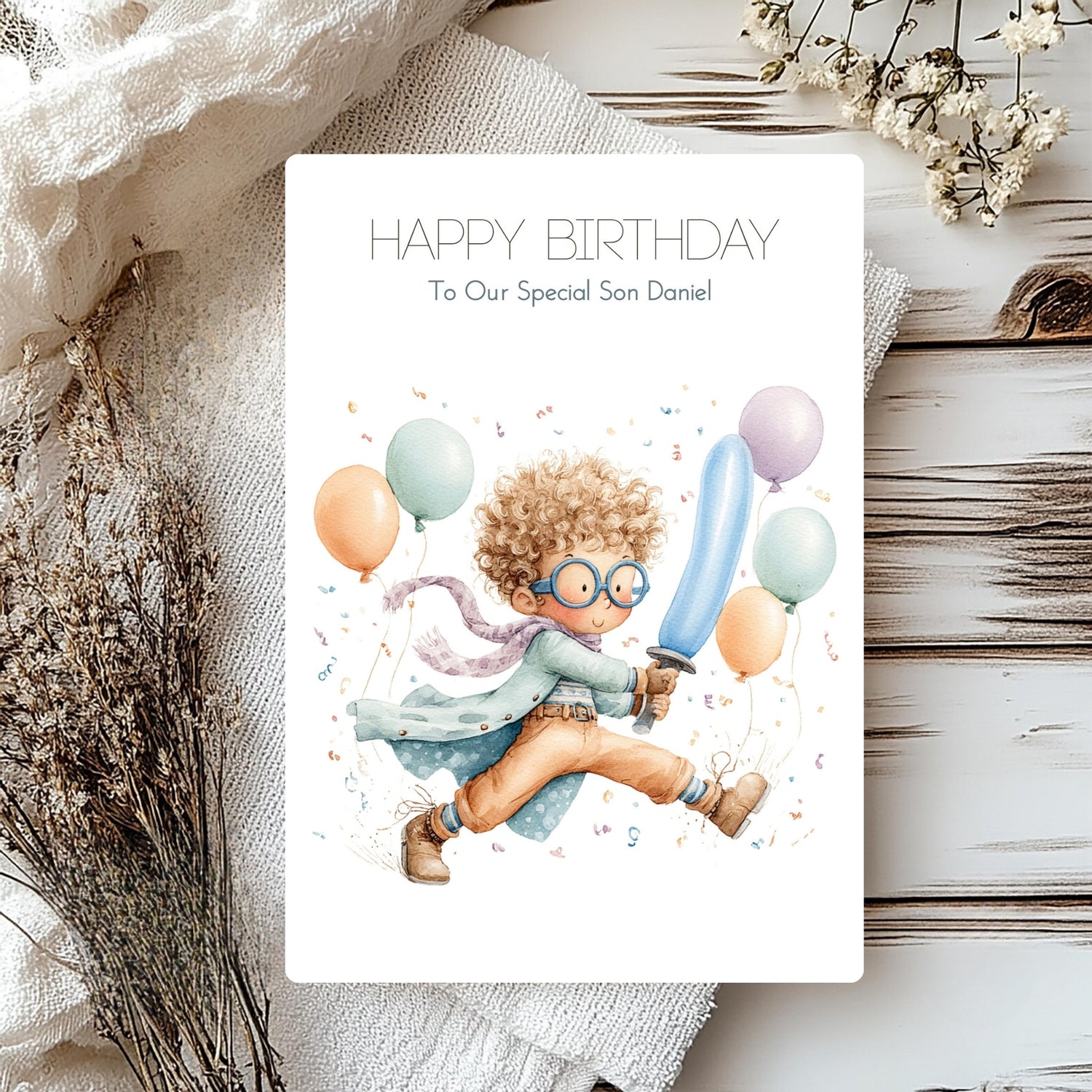Birthday card with a child holding balloons and a sword, surrounded by flowers on a wooden surface.