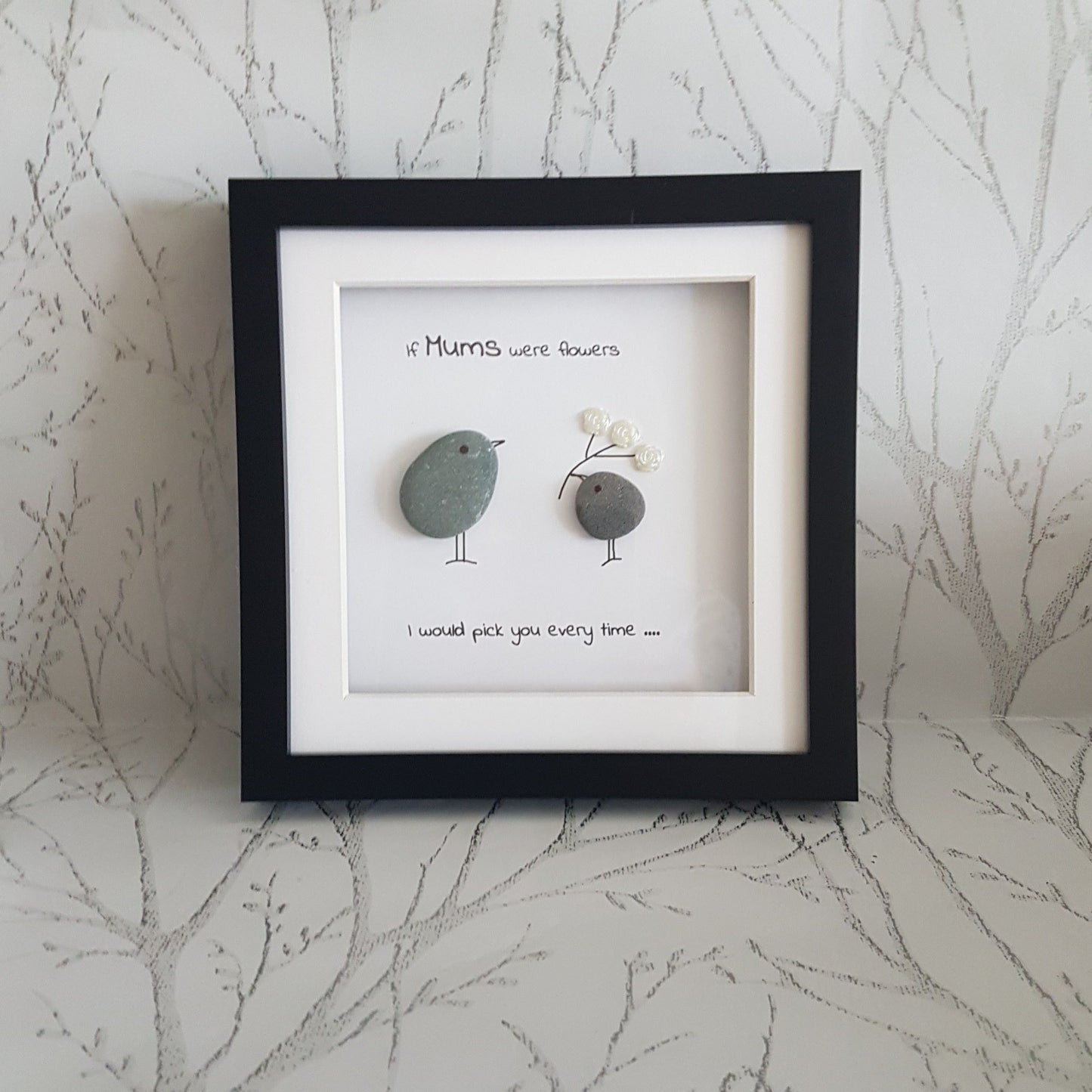 Pebble art framed gift for mum with text on a staged background.