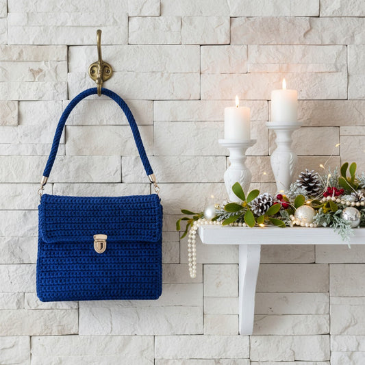 Blue handbag hanging on a wall hook next to a decorated shelf with candles and Christmas greenery.