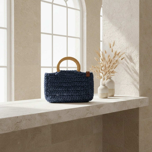 Blue crochet handbag on a sideboard with dried flowers in a vase