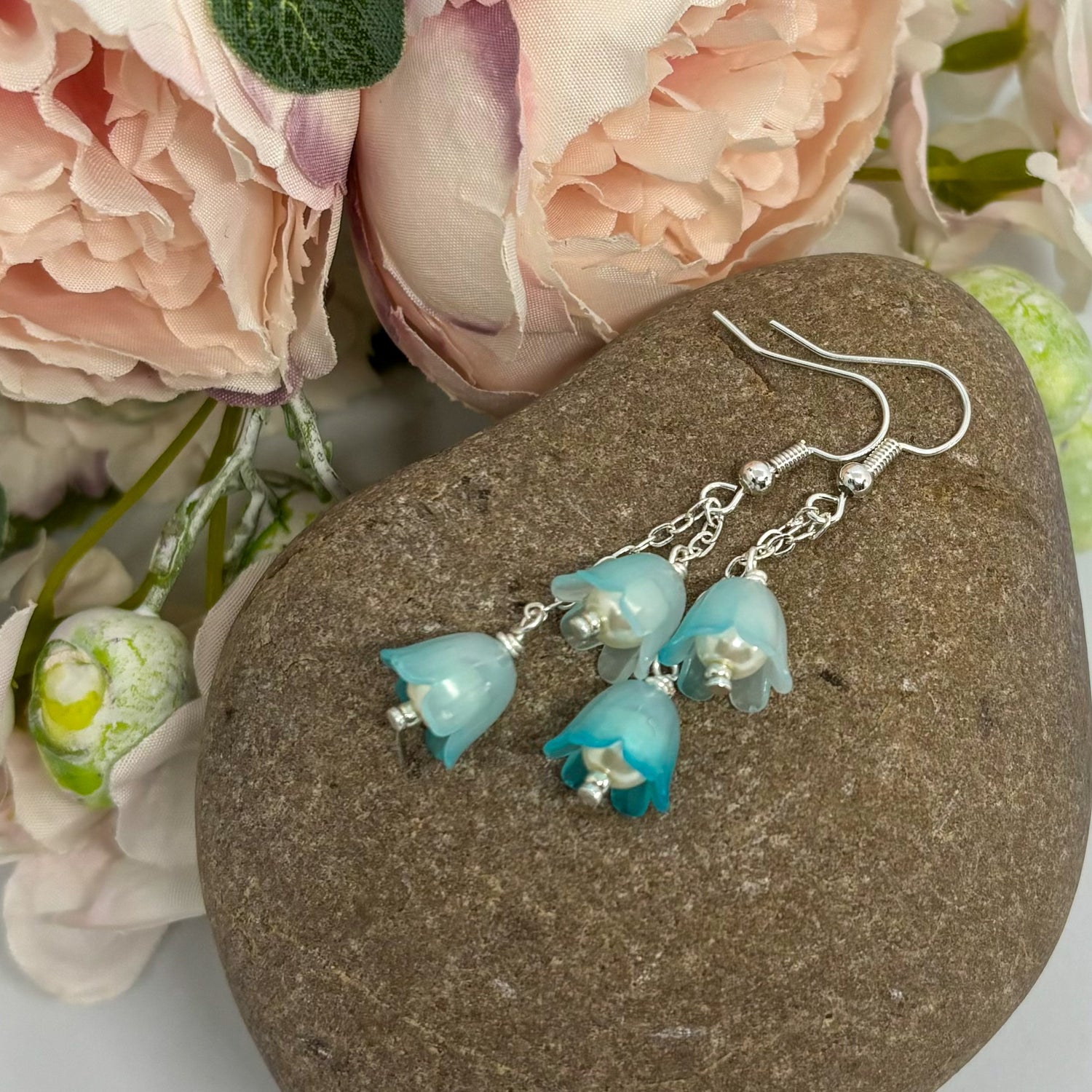 frosted blue earrings with silver hooks on a stone