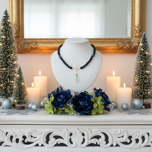 Pretty blue gemstone necklace with Christmas trees and candles on a necklace mannequin.