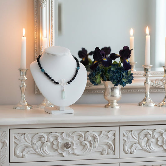 Gemstone Necklace on a mannequin bust with candles and flowers in the background