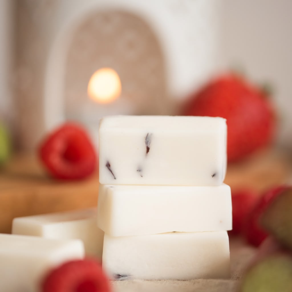 Stack of white wax melts with red fruits in the background