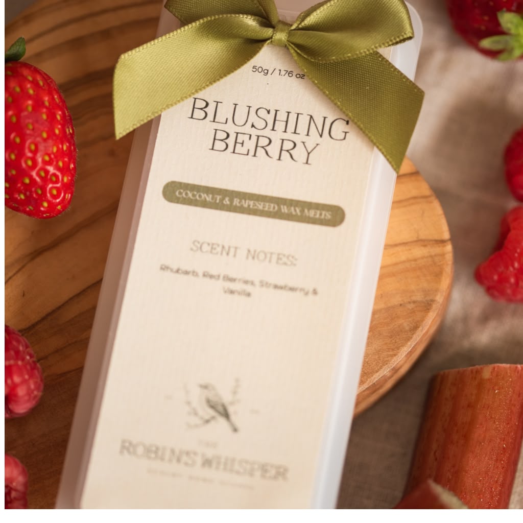 Wax Melts of Blushing Berry by Robins Whisper, wrapped in a gold ribbon, displayed on a wooden board with fresh strawberries.