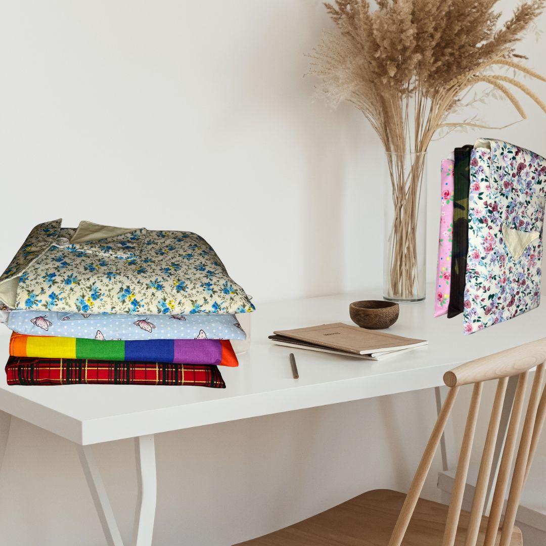 Range of book cosies shown on a desk with some notebook, a pen and some flowers in a vase