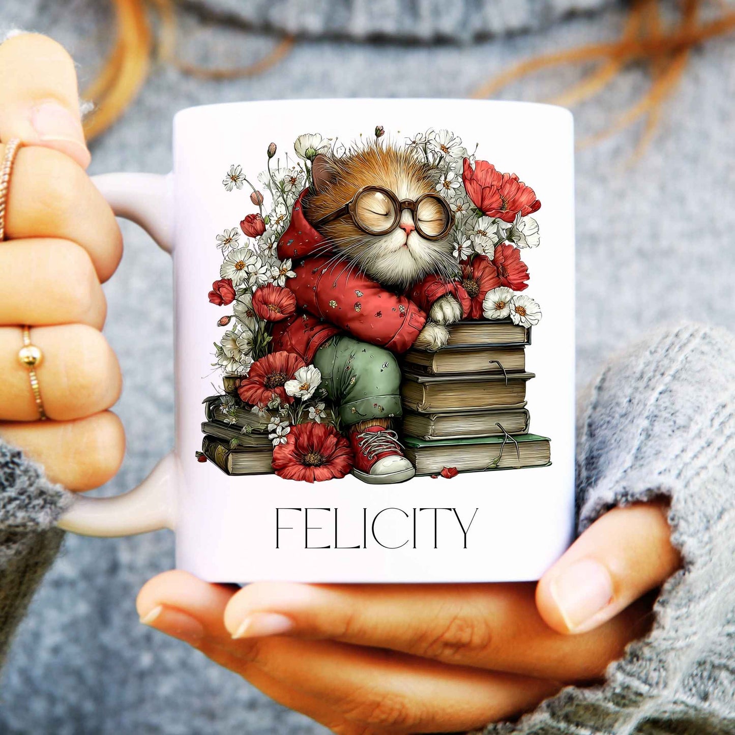 Mug with a cat illustration and 'Felicity' text held by hands.