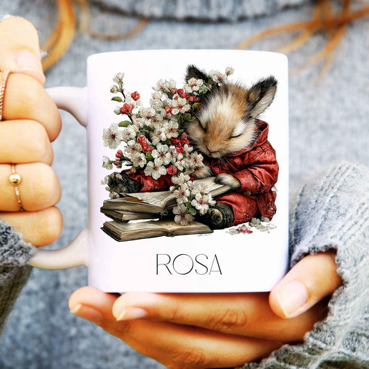 Person holding a mug with a design of a mouse and flowers, labelled 'ROSA'.