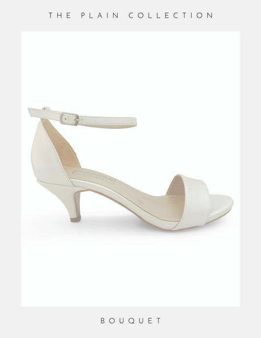 A white kitten heel bridal shoe with a peep toe design and ankle strap, from the Bouquet brand.