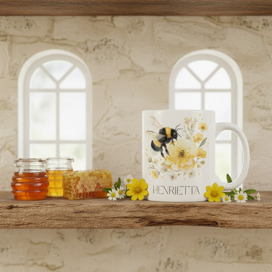 White mug with bee and floral design on a wooden shelf with honey jars and flowers.