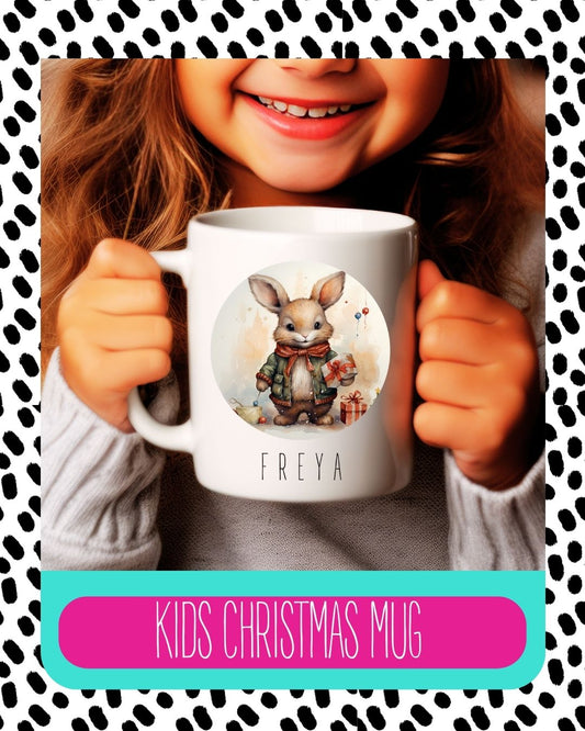A child holding a white ceramic mug with a personalised illustration of a bunny character in a Santa hat, with the text 'Kids Christmas Mug' on the image.