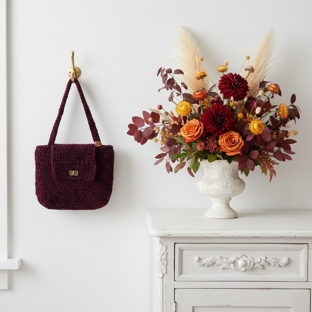 Crochet handbag hung on a wall next to a large vase full of flowers