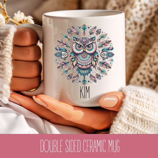 A white ceramic mug with a colourful owl design and personalised name 'Kim' held in a person's hand.