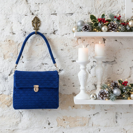 Blue handbag hanging on a textured white wall with festive decorations.