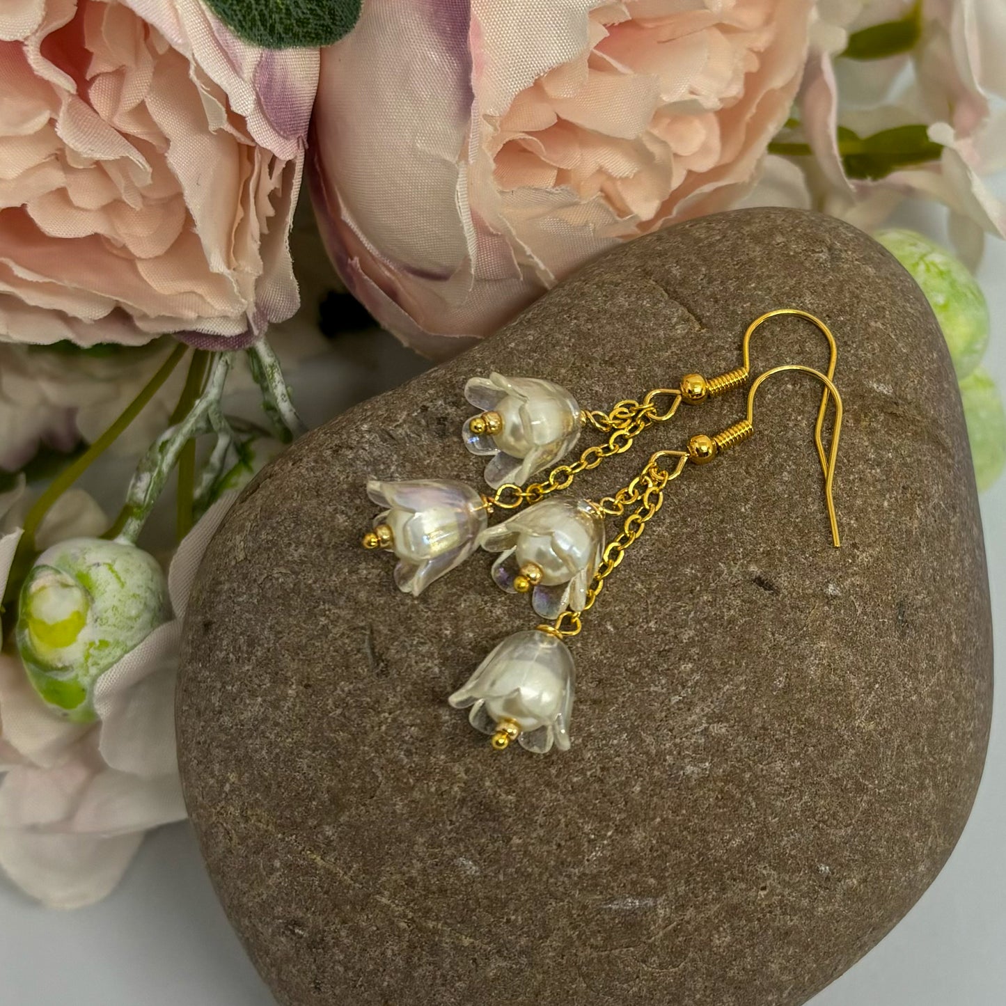 clear floral earrings with gold hooks on a stone