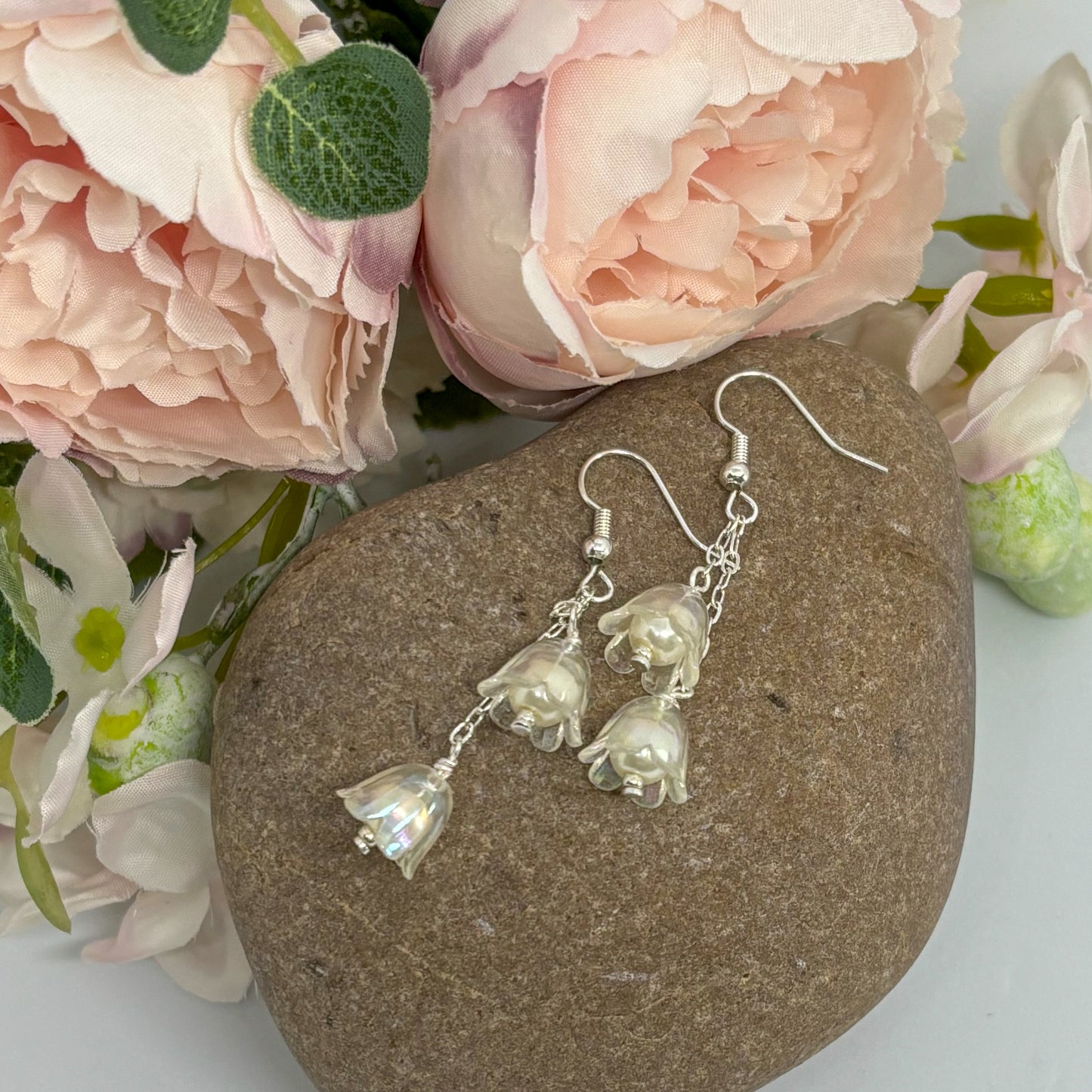 clear tulip earrings with silver hooks on a stone