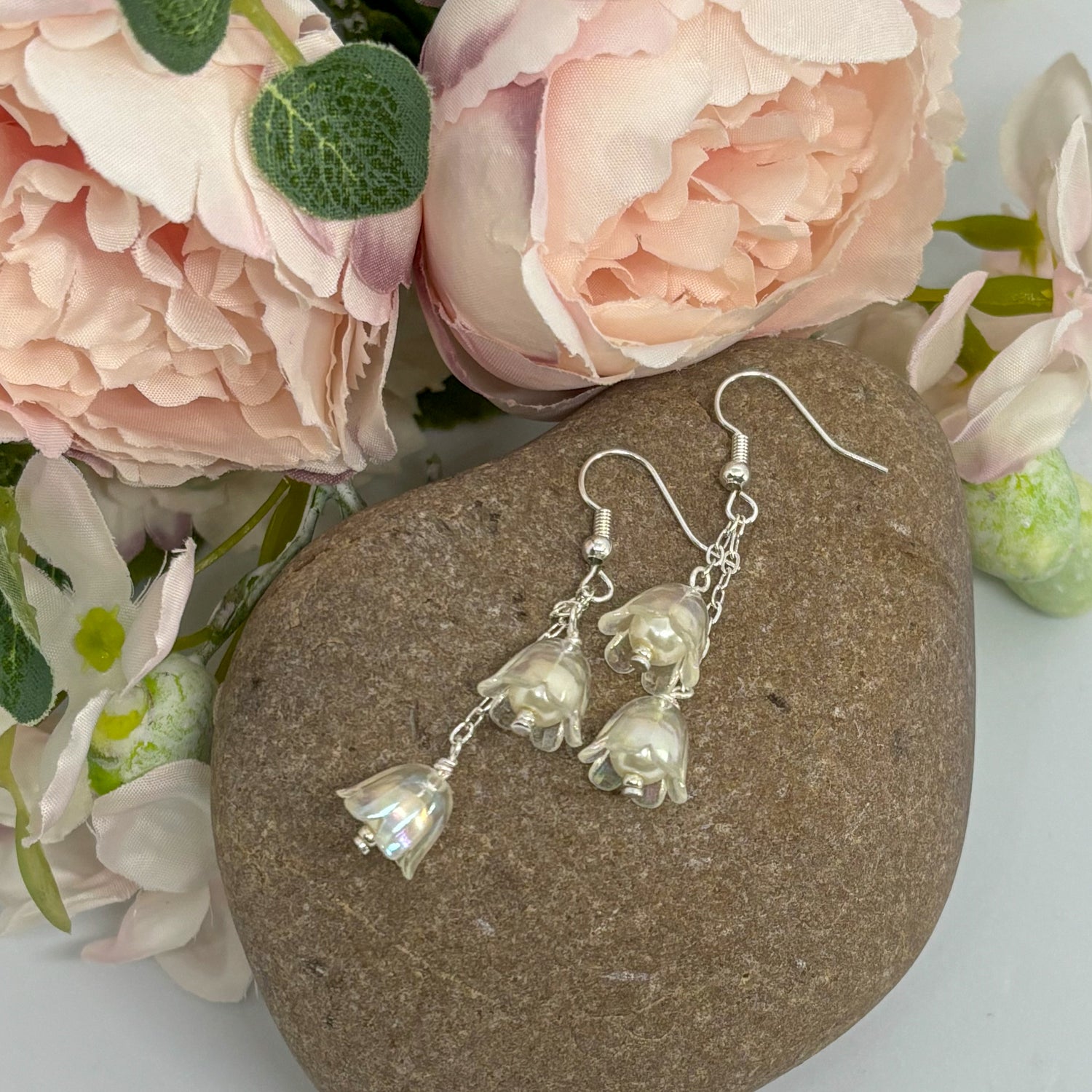 clear tulip earrings with silver hooks on a stone