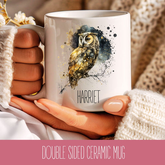 A white ceramic coffee mug with a printed owl design and the name 'Harriet' on the side, held in a person's hand.