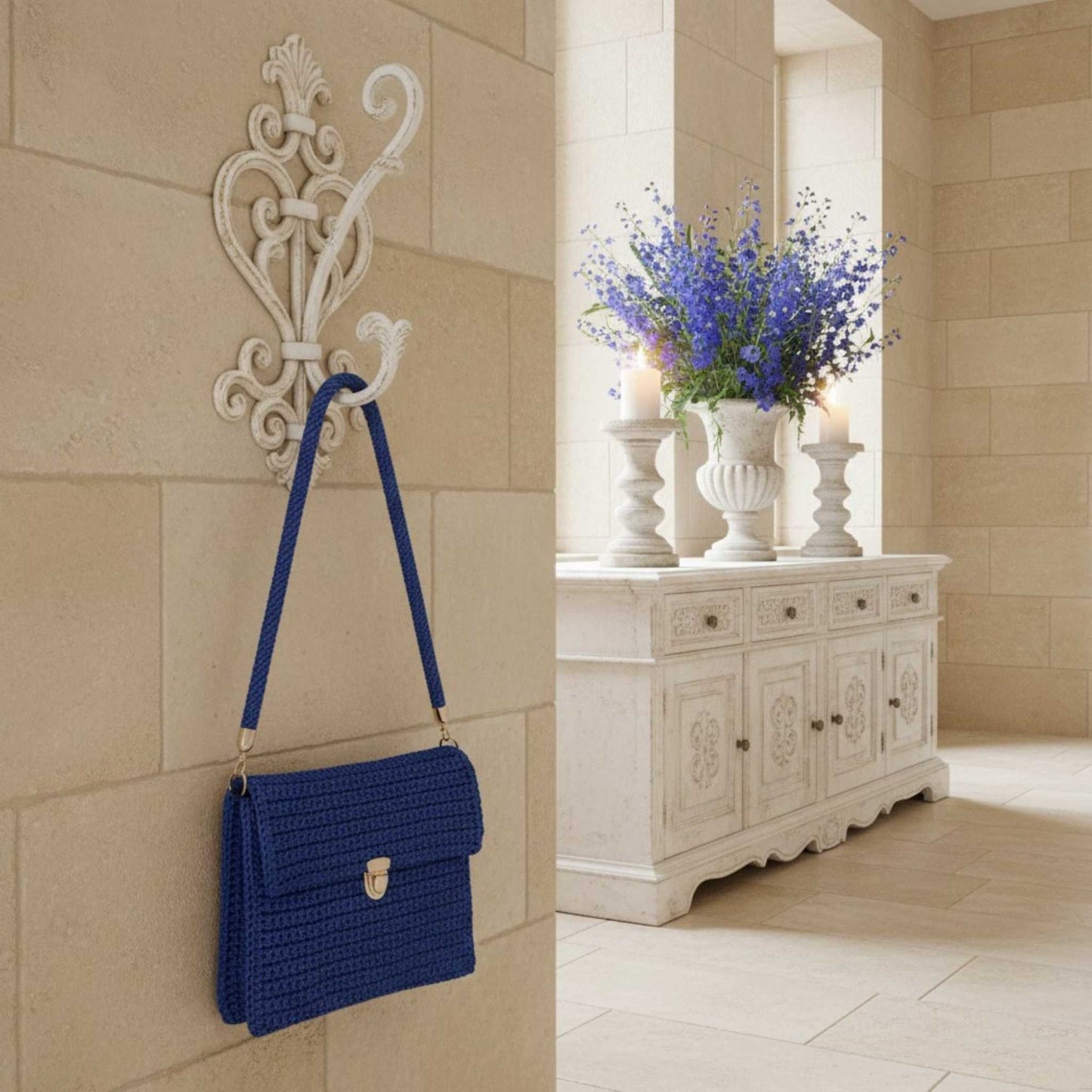 Crochet handbag hung on hook next to a sideboard with beautiful flowers.