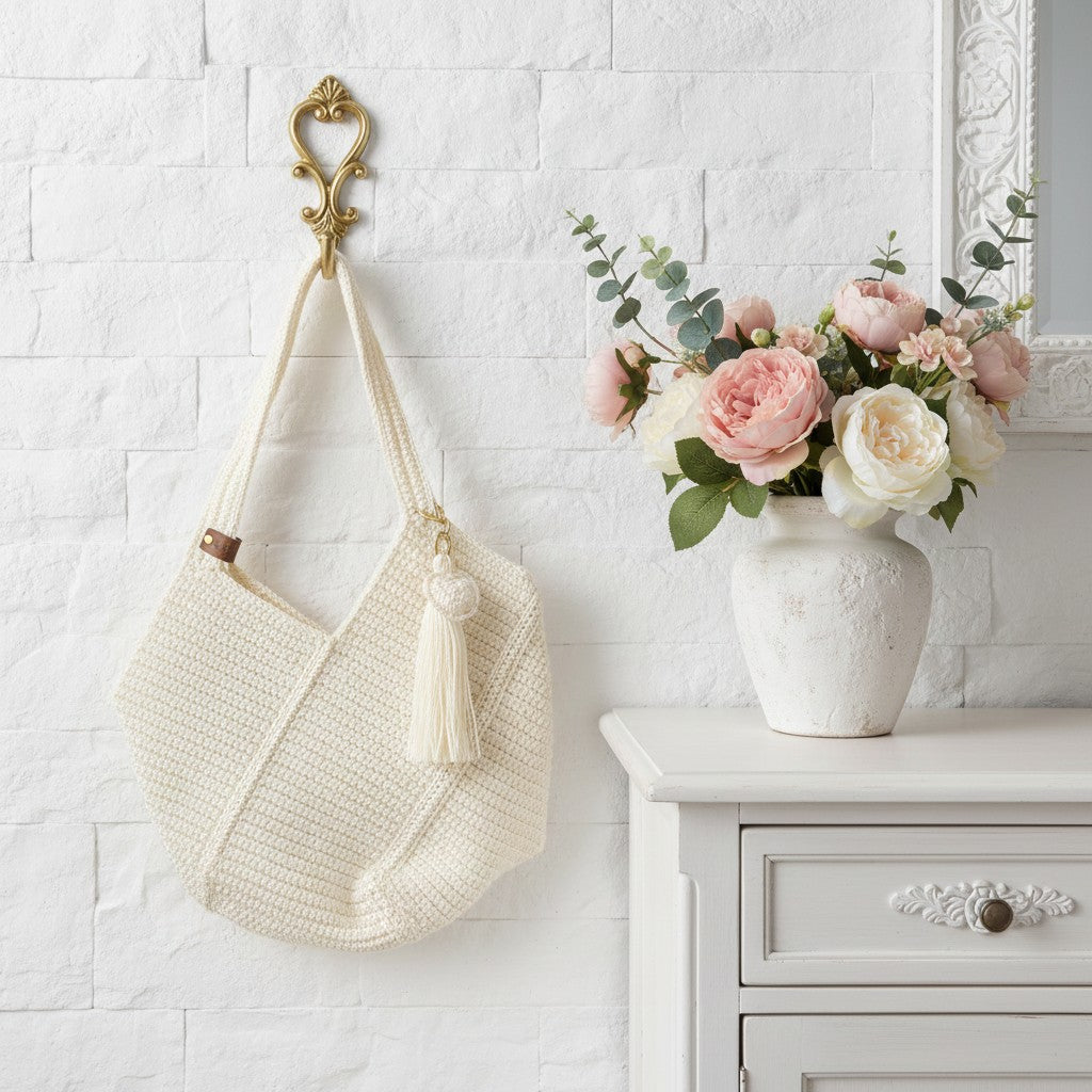 crochet shopper bag on a gold hook next to a sideboard with vase of flowers