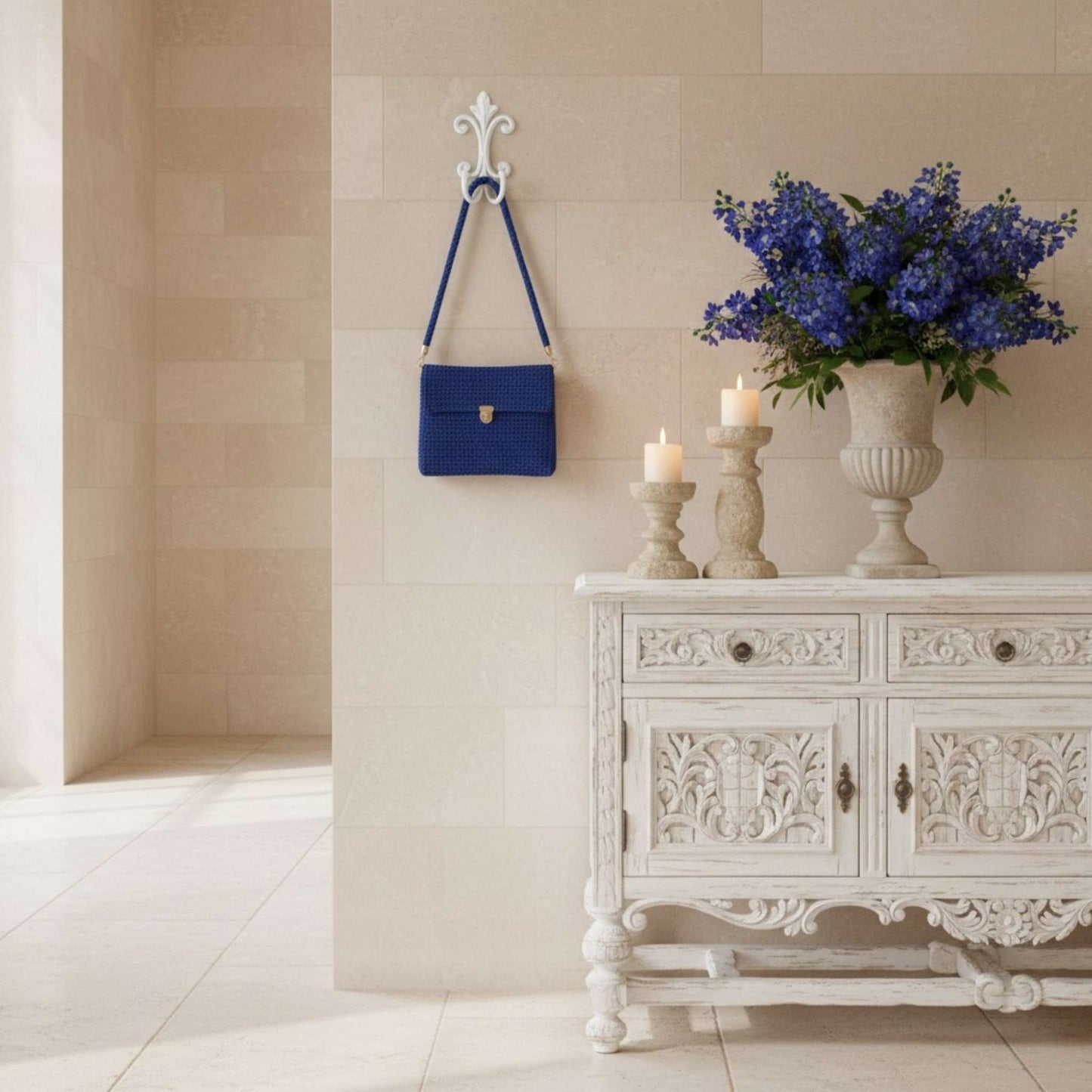 Decorative white cabinet with floral arrangement, candles, and blue handbag in a room.