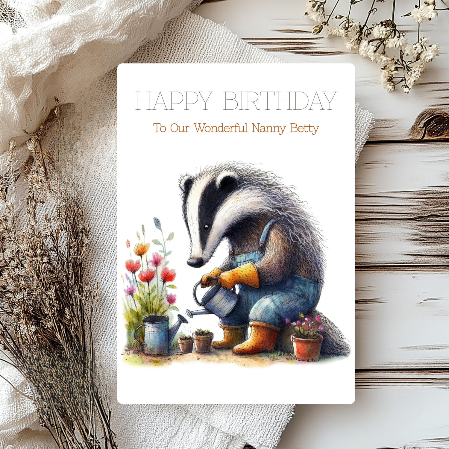 Birthday card with badger illustration watering plants on a textured surface.