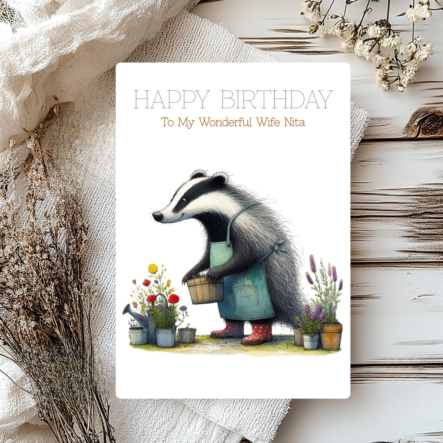Birthday card with a badger character gardening, surrounded by flowers and plants on a rustic wooden surface.