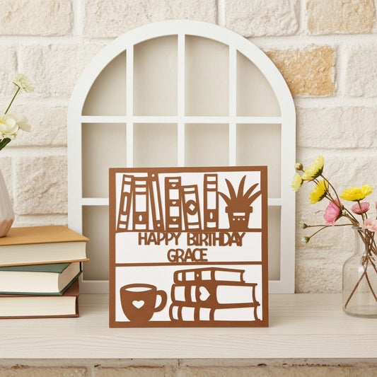Decorative bookish birthday card with 'Happy Birthday Grace' on a shelf with books and flowers.