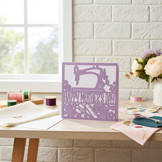 Purple 'Happy Mother's Day' card with sewing machine design on a wooden table.