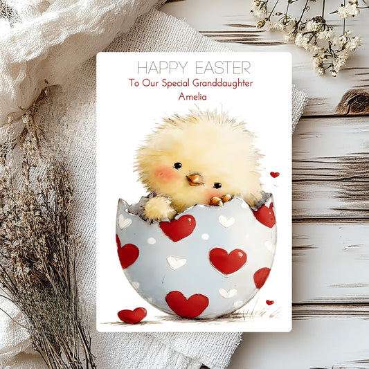 Easter card with a chick in a heart-patterned egg on a wooden surface.