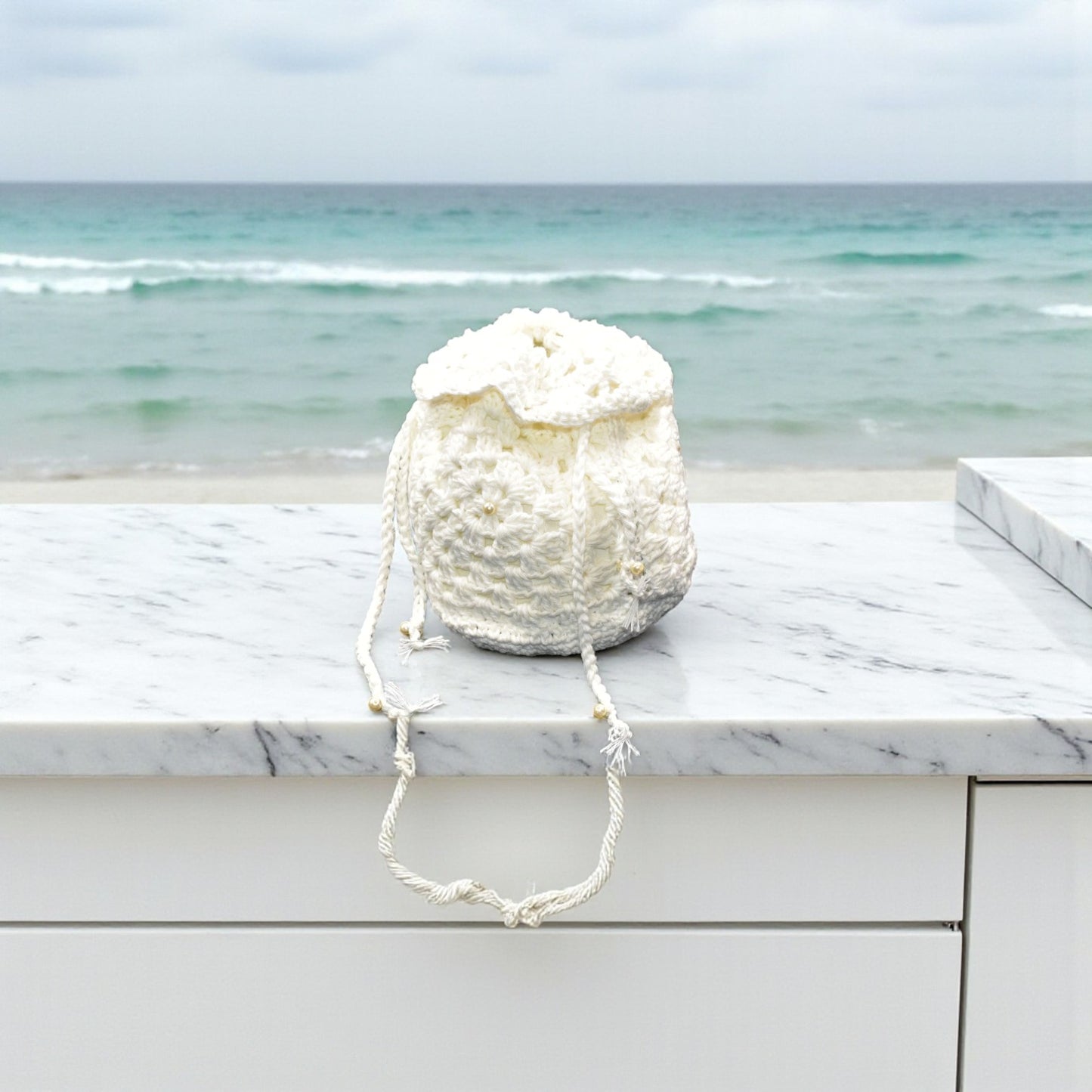 White crochet bag on a marble ledge with ocean view