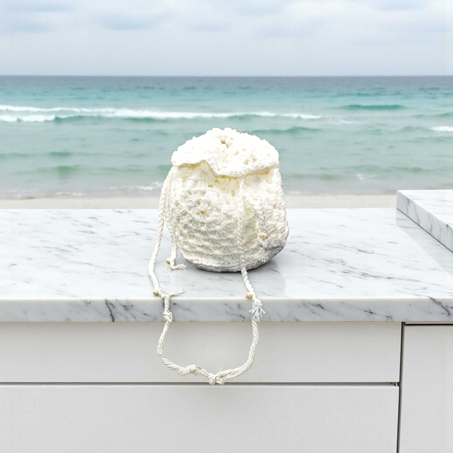 White crochet bag on a marble ledge with ocean view