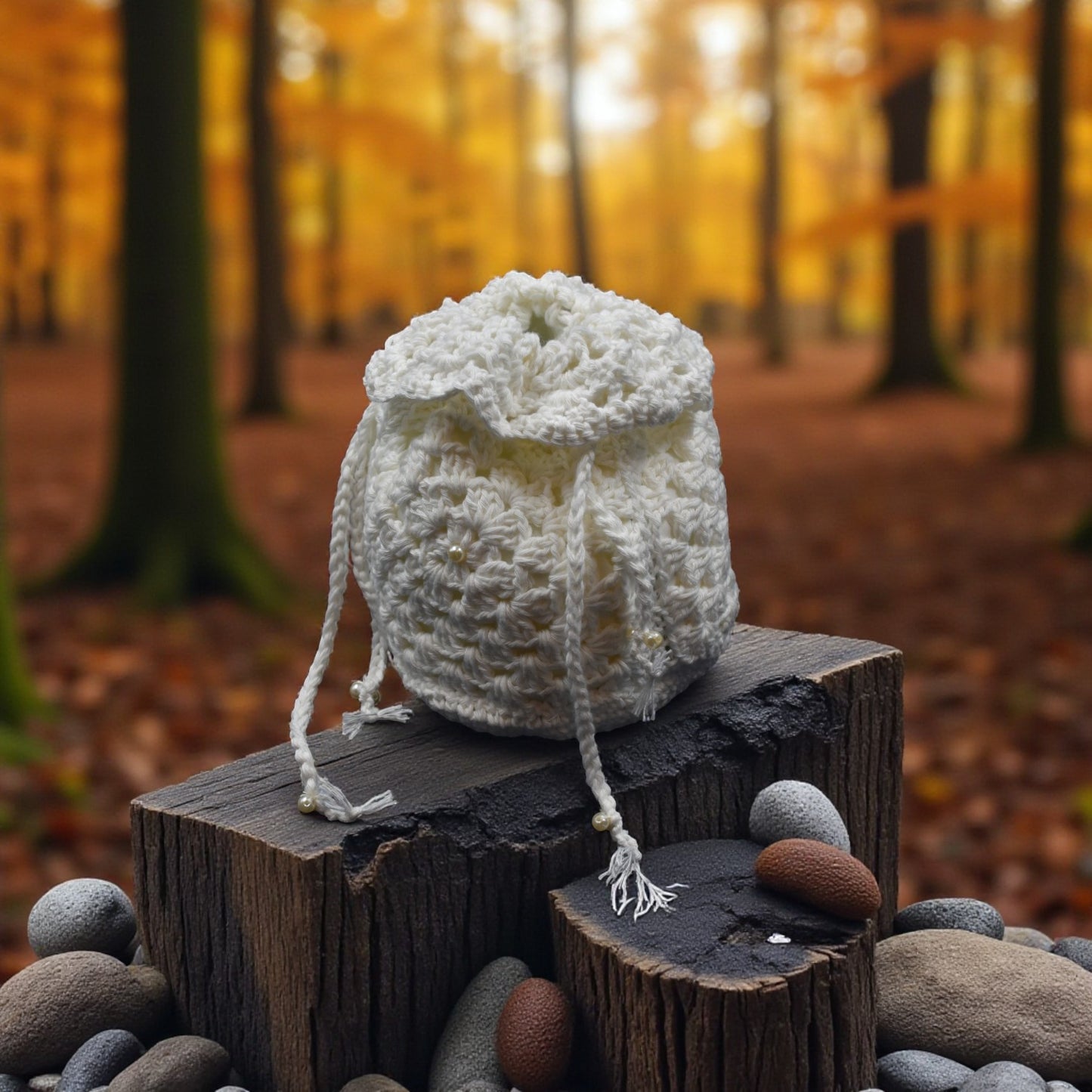 White drawstring crochet bag on a wooden log with a forest background