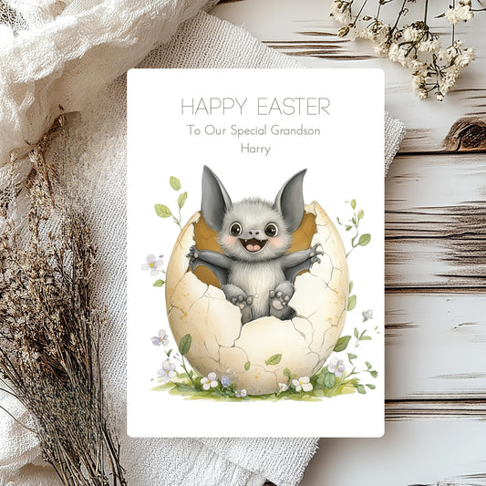 Easter card with a bat emerging from an egg, surrounded by flowers on a wooden surface.