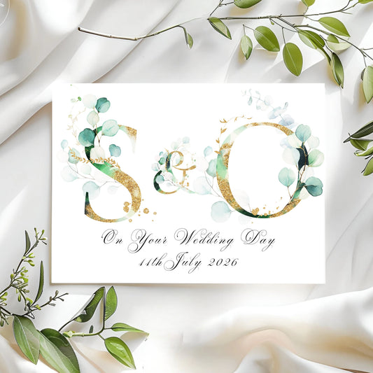 Wedding card with initials 'SO' and greenery on a white fabric background