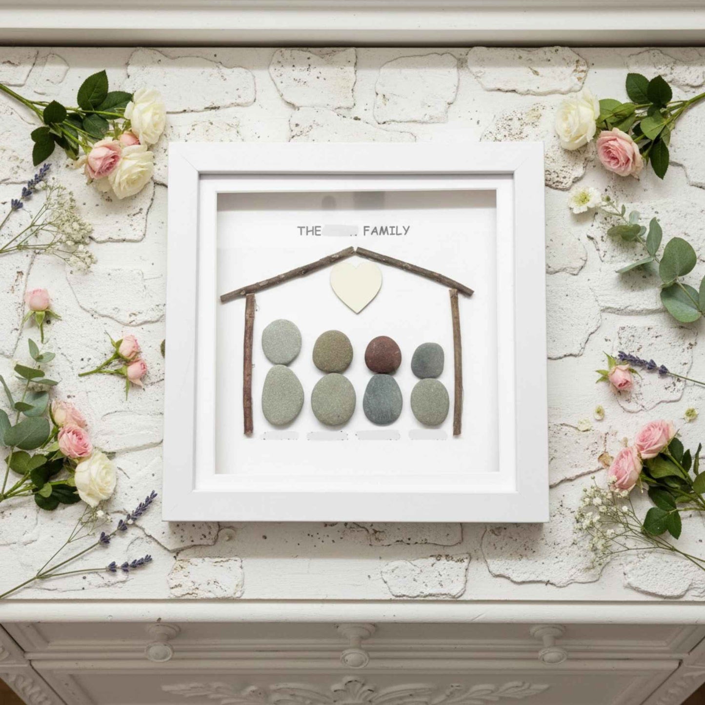 Framed artwork with pebble family design on a decorative surface with flowers
