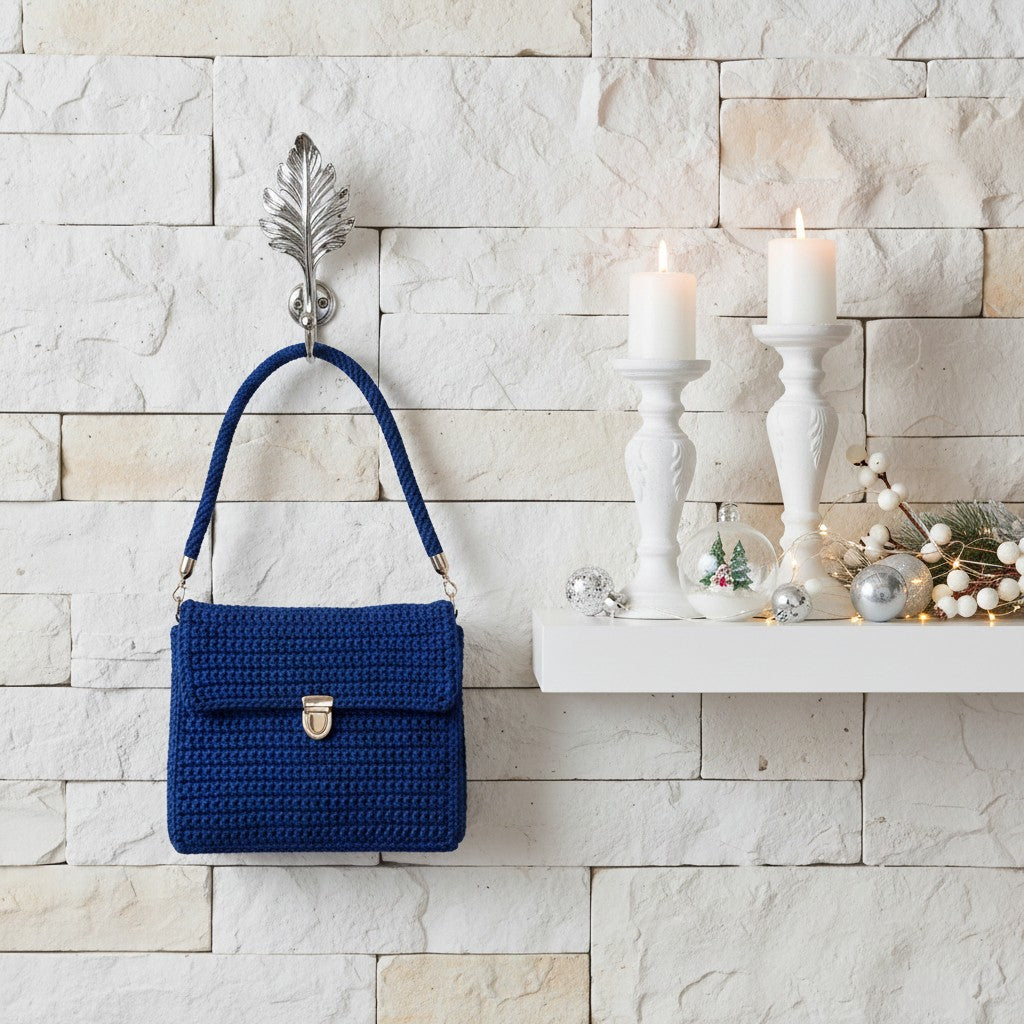 Blue handbag hanging on a wall hook with decorative candles and ornaments on a mantel.
