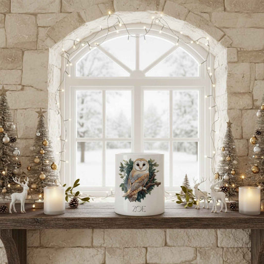 Decorative candle with owl design on a mantelpiece in front of a window with Christmas decorations.