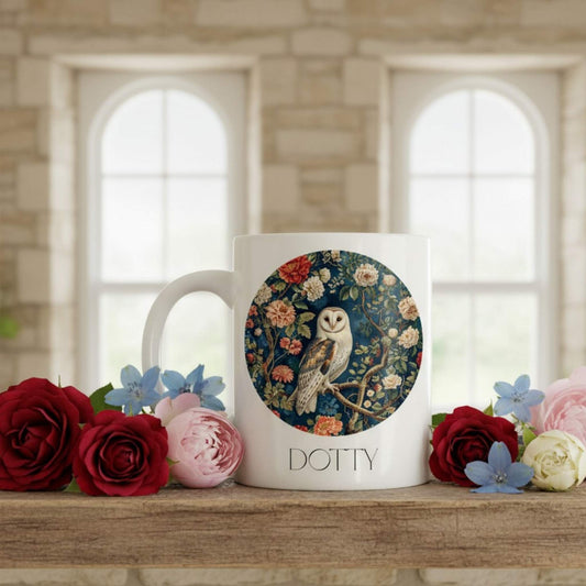Mug with owl design and 'Dotty' text, surrounded by flowers on a wooden surface.