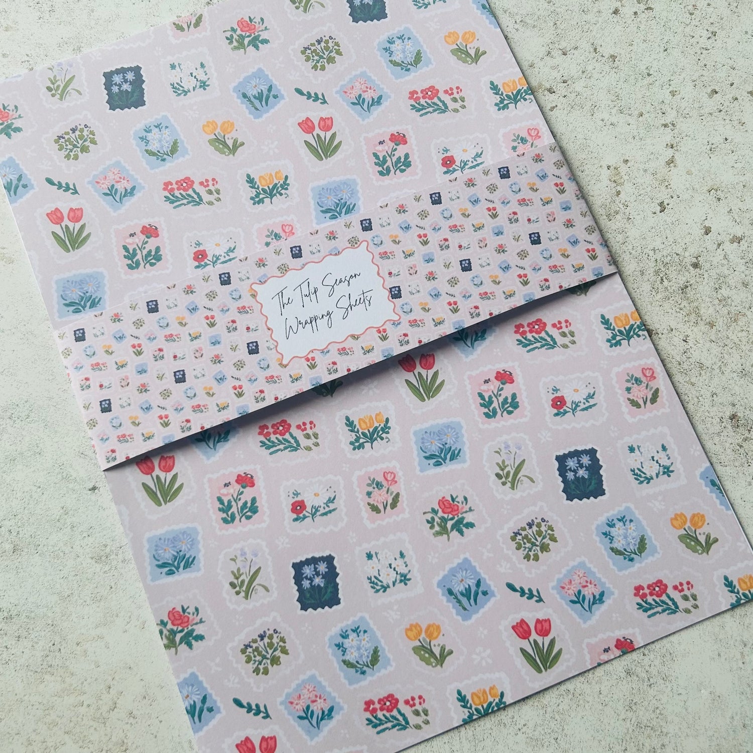 Two sheets of floral patterned paper on a textured surface