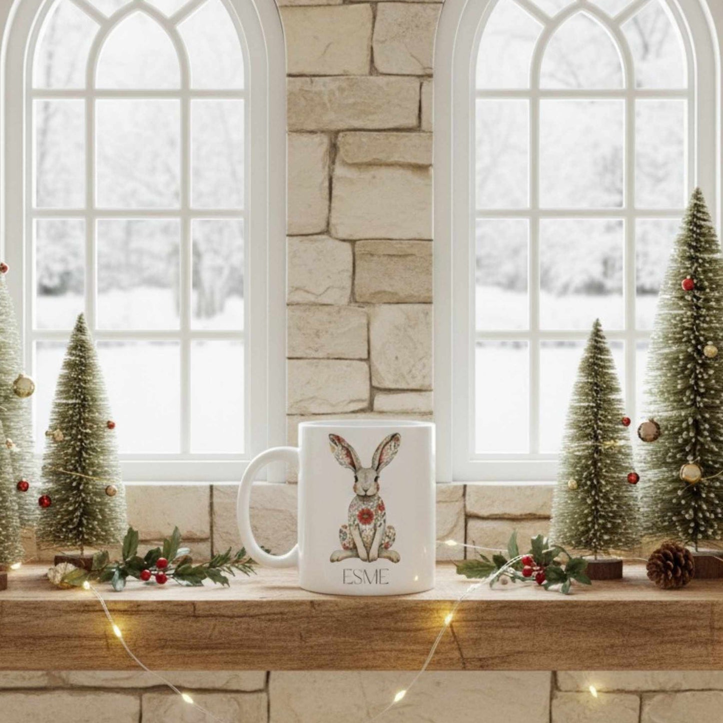 Mug with a hare design on a windowsill with decorative Christmas trees and lights.