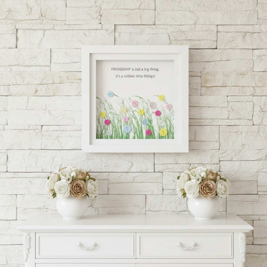 Framed artwork with floral design and text on a stone wall with two flower vases below.