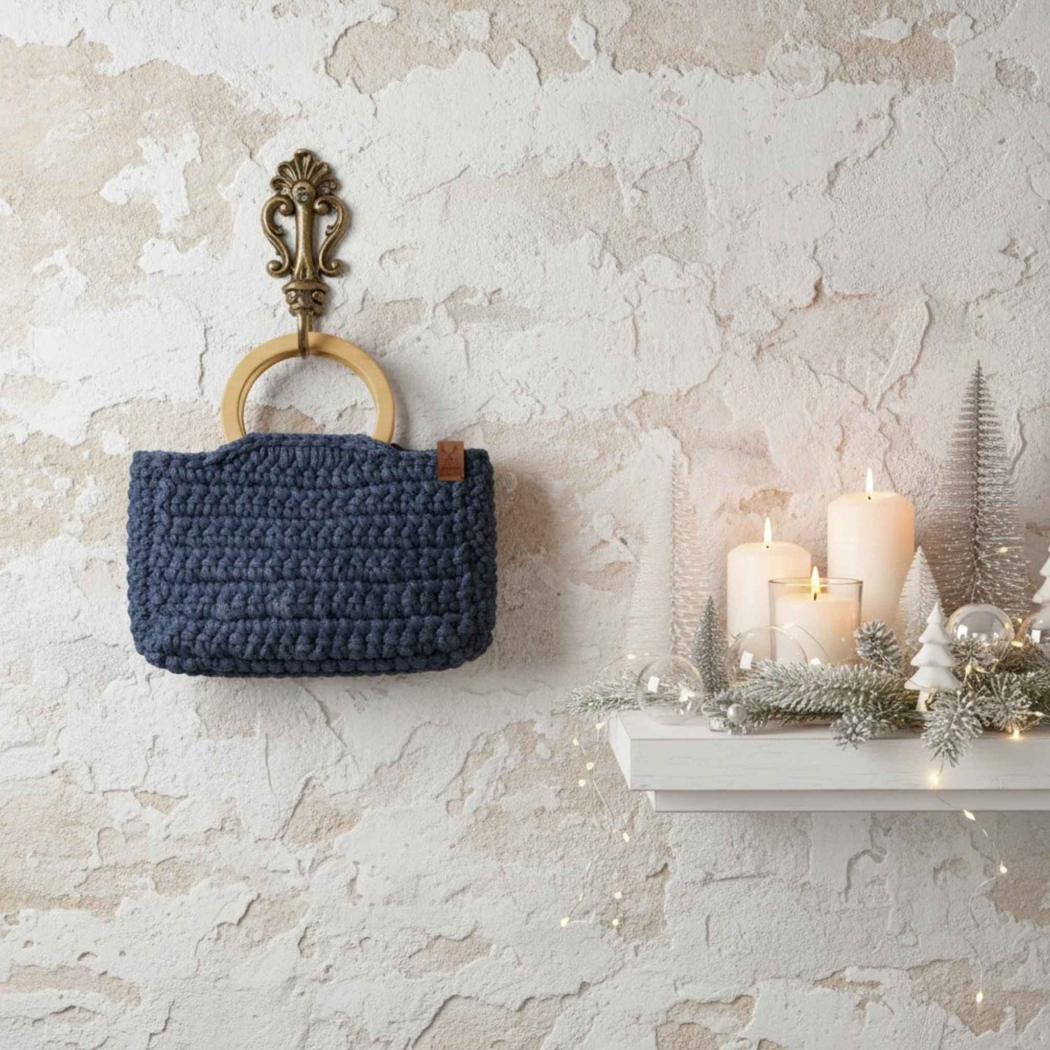 Blue woven basket with wooden handle against a textured wall with candles and decorative items.
